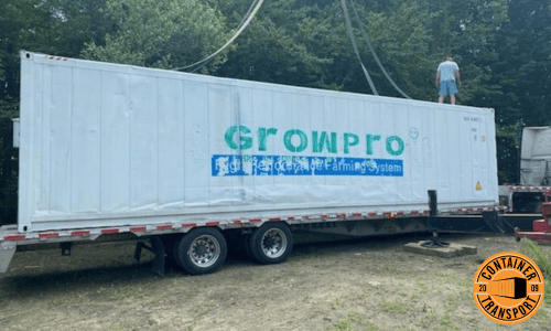 Growpro container lifted by crane on trailer for transport.