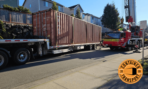 Container being moved on a step deck trailer.