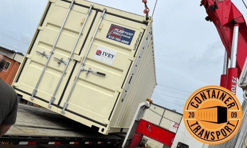 Container being lifted by crane on a trailer.