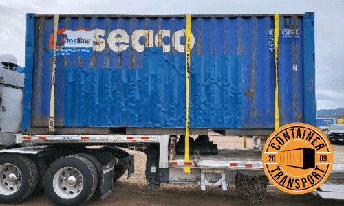 Container strapped on a Step Deck trailer.
