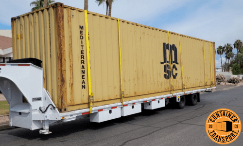 Container strapped onto a Flatbed Gooseneck trailer for transport.