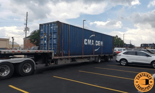 Container Strapped onto a step deck trailer for transport.