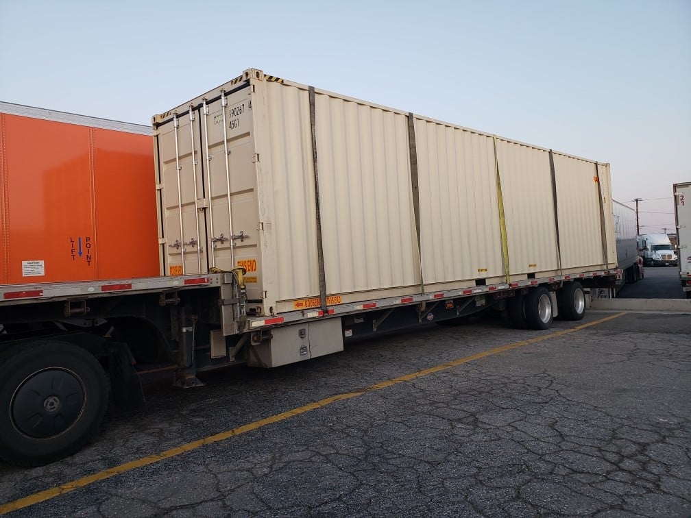 Container secured to a step deck trailer for international transport.