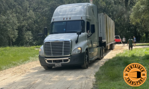 Container being transported on a step deck trailer.