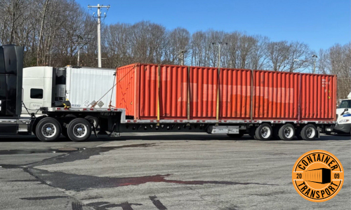 Large container being transported on a step deck trailer.