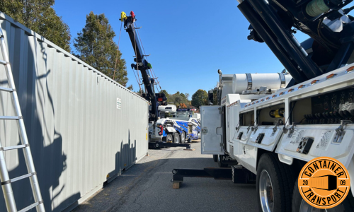 Crane lifting 40ft HC container for transport.