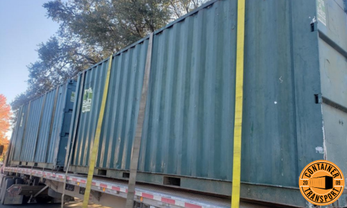 Transporting two containers strapped onto a flatbed trailer.