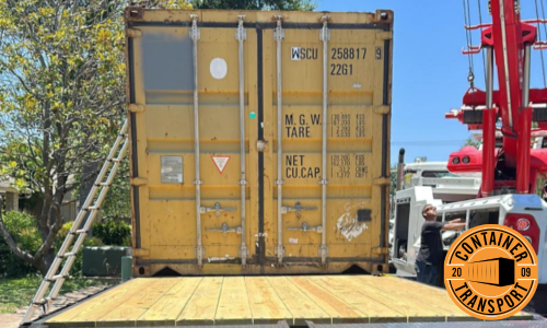 Container lifted by a crane on a trailer.
